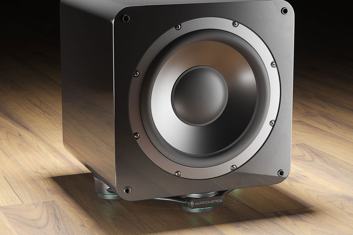 IsoAcoustics Aperta Sub — sotto un subwoofer su un pavimento in legno